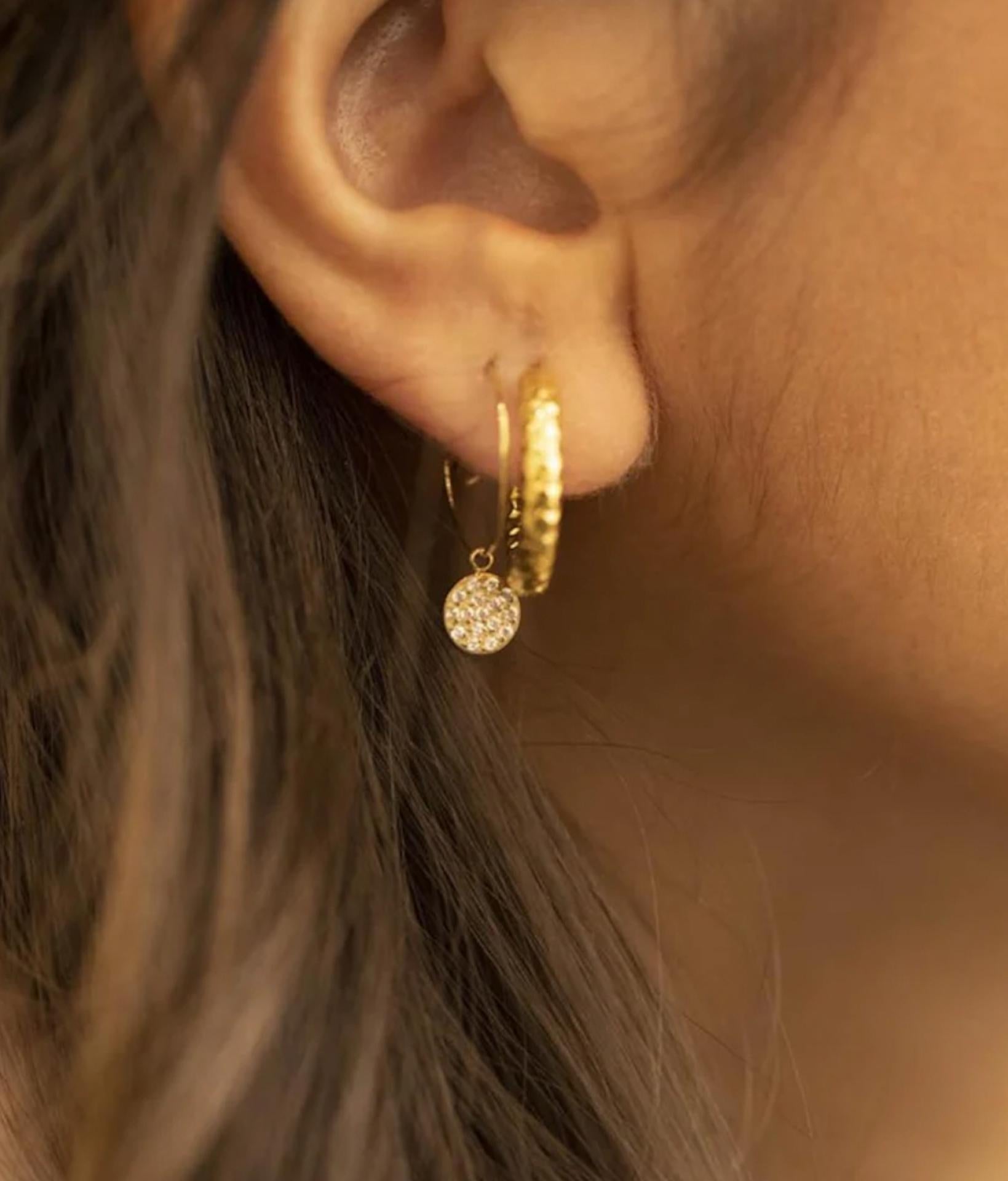 Nahaufnahme von einer jungen Frau, die zwei zierliche Ohrringe mit Zirkonia Steinen trägt